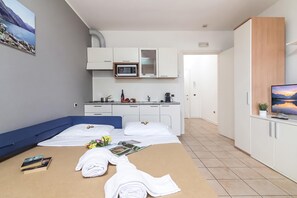 A hotel room with a bed, a desk, a microwave, a TV, and a view of the mountains. - Porto Letizia P19, Porlezza, Italy (Porlezza)