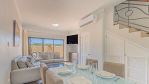 A dining area with a table set for four, a sofa, and a view of the outdoors. - LUX 2BR Condo | Gold Coast Pools & Gym Near Malmok (Noord)