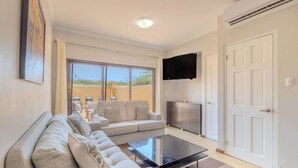 A modern living room with a sofa set, a coffee table, and a flat-screen TV mounted on the wall. - LUX 2BR Condo | Gold Coast Pools & Gym Near Malmok (Noord)