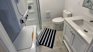 Een kleine badkamer met douche, toilet en wastafel.