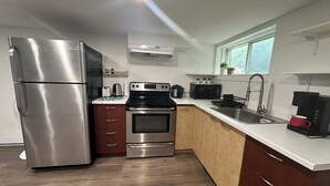 Een moderne keuken met roestvrijstalen apparatuur, houten kastjes en een raam dat natuurlijk licht binnenlaat.