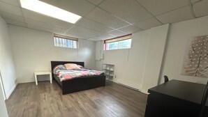 Een slaapkamer met een bed, nachtkastje, bureau en een boekenkast.