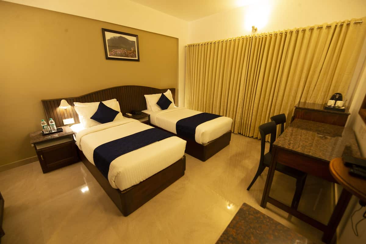 A hotel room with two beds, a desk, and a chair.