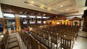 Una sala àmplia amb files de cadires i taules de fusta, un sostre alt amb il·luminació empotrada i un disseny arquitectònic tradicional.