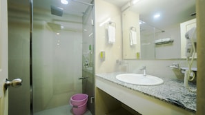 A modern bathroom with a glass-enclosed shower, a white sink, and a granite countertop. - Hotel Guruvayur Darshan (Chavakkad)