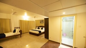 Habitació d'hotel amb un llit, un sofà, un ventilador de sostre i una porta que dona a un bany.