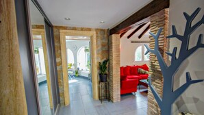 Un intérieur spacieux avec un canapé rouge, des piliers en pierre et une décoration murale en forme d’arbre.