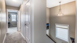 A hallway with beige walls, white doors, a ceiling light, and a window with blinds. - Rome, Sweet Home. 

Spacious 4 Bedroom Single detached house - 60 mins to Banff. (Calgary)