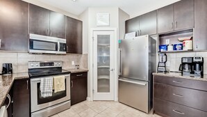 A modern kitchen with stainless steel appliances, dark cabinetry, and a tiled floor. - Rome, Sweet Home. 

Spacious 4 Bedroom Single detached house - 60 mins to Banff. (Calgary)