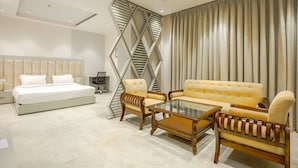 A modern hotel room with a bed, two sofas, a coffee table, and a TV. - Hotel The Reef (Mohali)