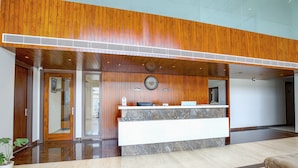 A reception area with a wooden ceiling, a marble reception desk, and a clock on the wall. - Hotel The Reef (Mohali)