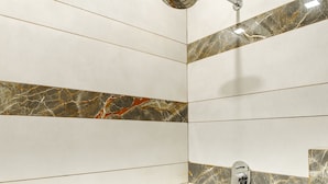 A shower with a handheld showerhead, a wall-mounted control, and a drain. - Hotel The Reef (Mohali)