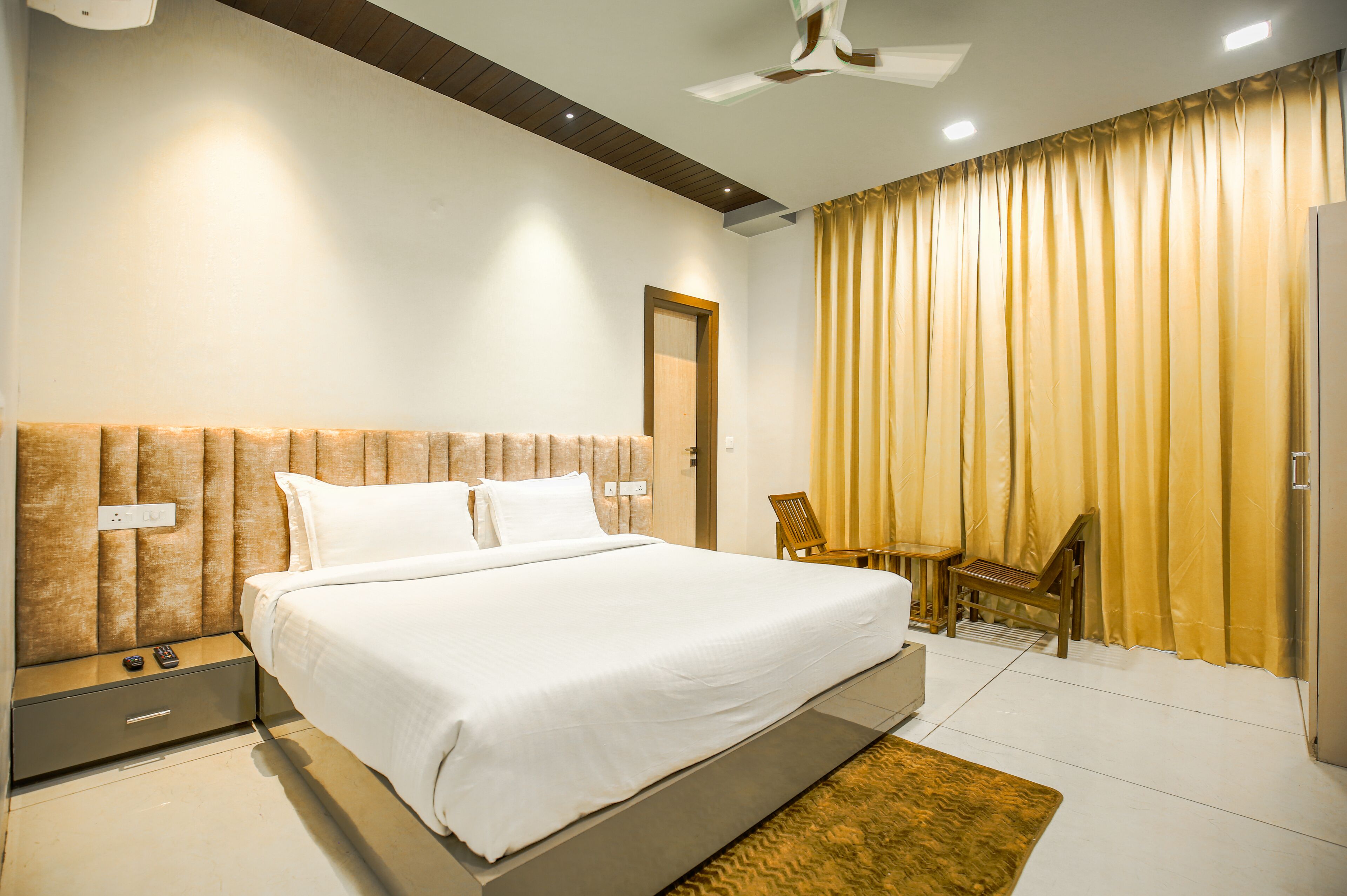 A modern bedroom with a large bed, bedside tables, a desk, and a chair.