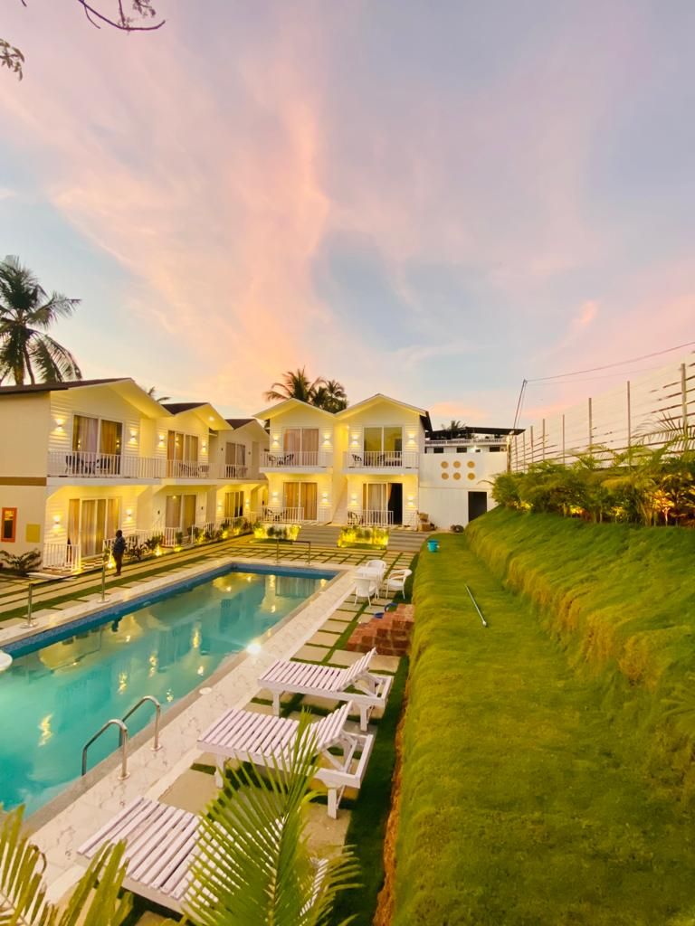Un hotel con piscina, varios balcones y un césped bien cuidado.