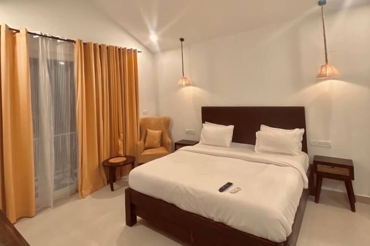 Een moderne slaapkamer met een groot bed, twee nachtkastjes, een stoel en een plafondventilator.