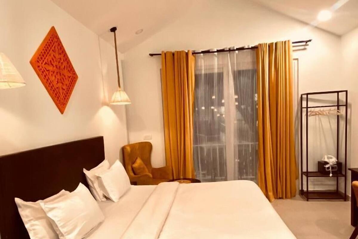 Een moderne slaapkamer met een groot bed, hoofdbord, nachtkastje, stoel, kledingkast en plafondventilator.