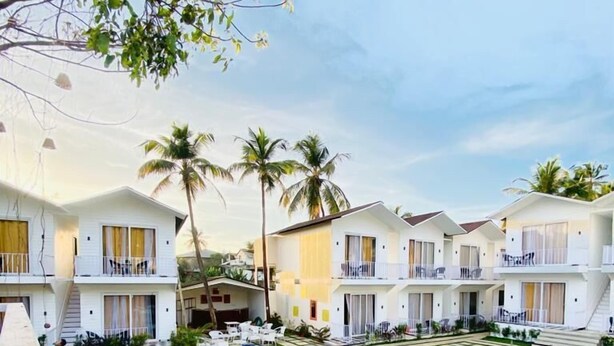 A resort with multiple white buildings, a central swimming pool, and outdoor seating areas. - Tvessa A Boutique Hotel Goa (Ashvem)