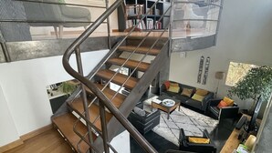 Ein modernes Interieur mit einer Wendeltreppe, einem Wohnbereich mit Sofa und Couchtisch sowie einem Bücherregal.