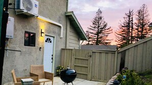 Un cortile con un barbecue, una recinzione in legno e una sedia.