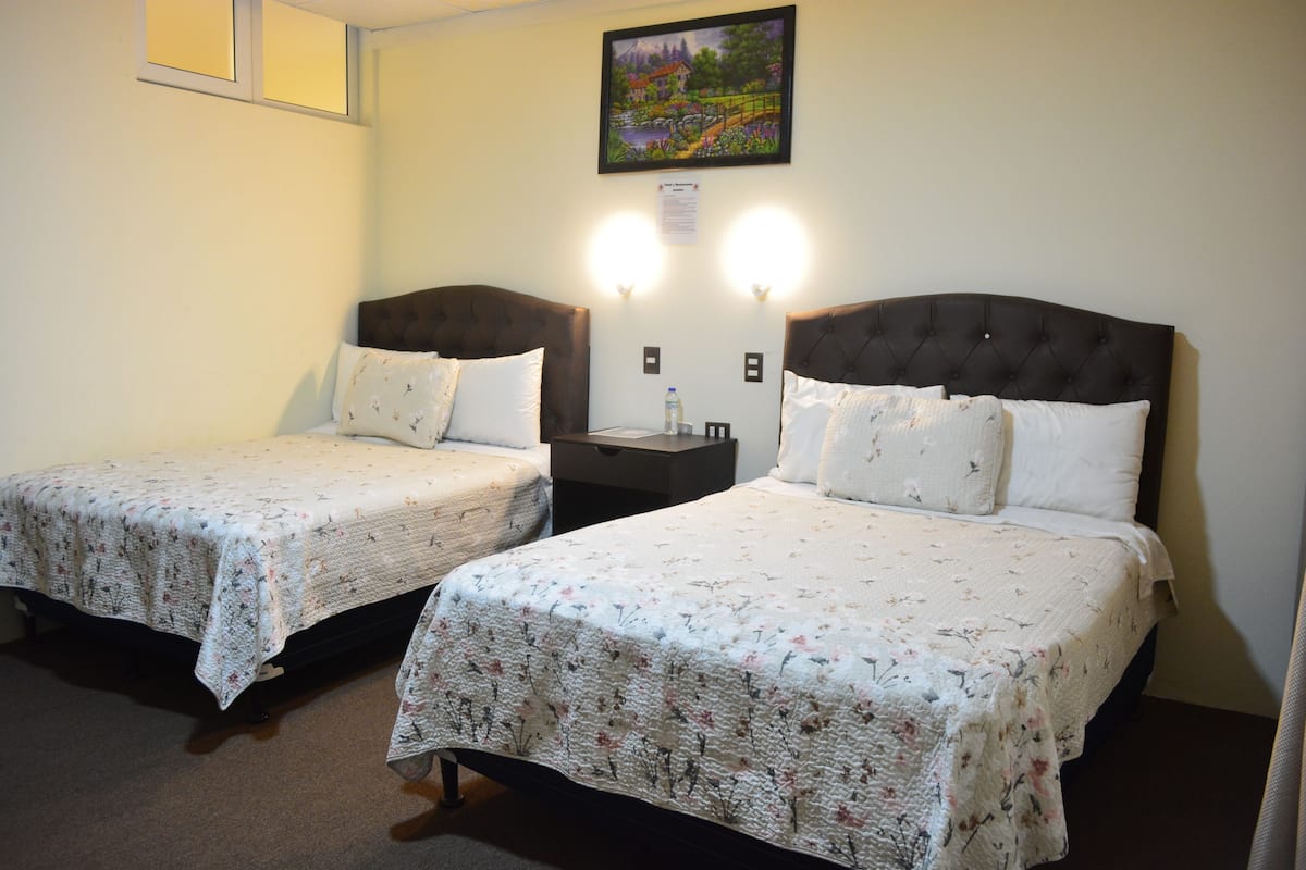 Two twin beds with floral bedding, bedside tables, and a painting on the wall.