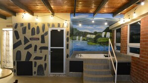 A spa area with a sauna, a mural of a waterfall, and a staircase leading to a window overlooking the spa. - Hotel y Restaurante Premier  (La Esperanza)