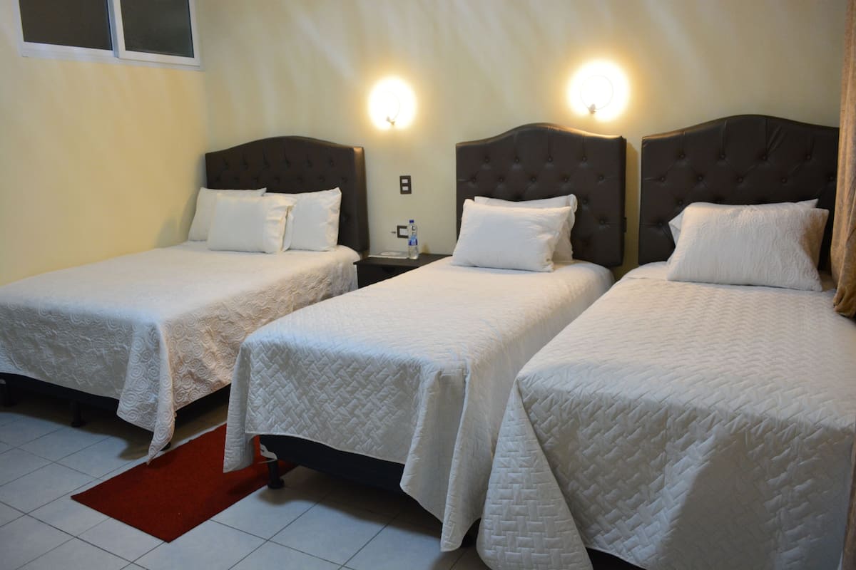 A hotel room with two single beds, each with a headboard and a nightstand.