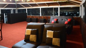 A rooftop lounge with leather seating, a wooden ceiling, and large windows overlooking a cityscape at night. - Hotel y Restaurante Premier  (La Esperanza)