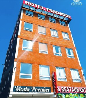 Een hotelgebouw met een bord waarop 'Hotel Premier' en 'Moda Premier & Restaurant' staat.