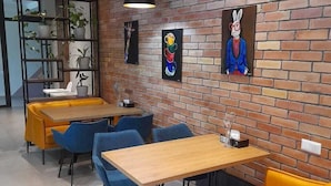 A modern dining area with brick walls, wooden tables, and yellow cushioned booths. - Hotel 78 Cafe (Karakol)