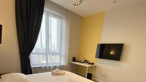 A hotel room with a bed, a desk, a TV, and a window with curtains. - Hotel 78 Cafe (Karakol)