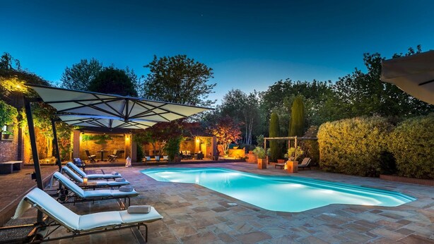 Piscina con sillas de descanso y un patio cubierto.