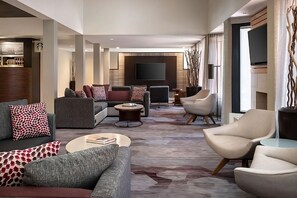 Ein modernes Wohnzimmer mit einer Eckcouch, Sesseln, einem Couchtisch und einem an der Wand befestigten Flachbildfernseher.