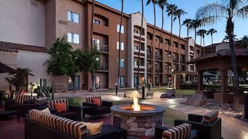 A hotel courtyard with outdoor seating and a central fire pit.