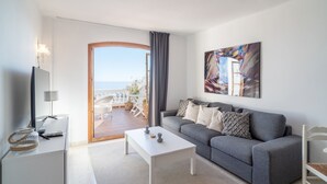 Una sala de estar moderna con un sofá gris, una mesa de centro blanca y un ventanal con vistas al exterior.