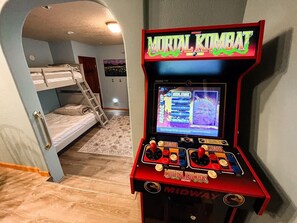 A room with bunk beds, a console game machine, and a small rug. - Perfect Spot | Hot Tub & Sauna | Sleeps 15 (Whitefish)