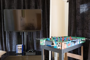 Una habitación con mesa de fútbol, televisor y una pila de DVDs sobre una mesa.