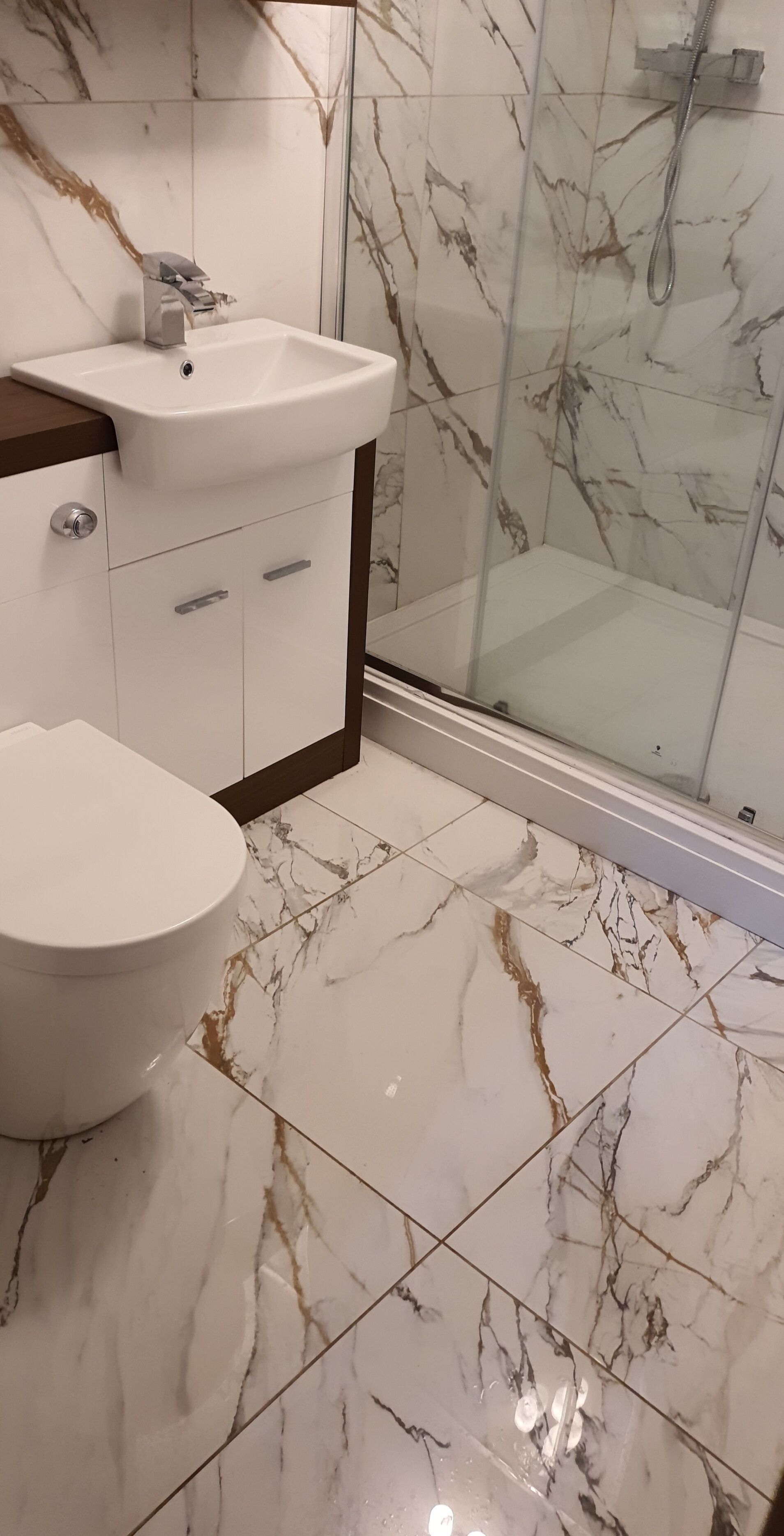 A bathroom with a white sink, a toilet, and a glass shower enclosure.