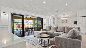 Ein modernes Wohnzimmer mit einem grauen Ecksofa, einem runden Couchtisch und einem Essbereich mit Stühlen und einem Tisch.
