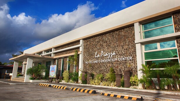 A hotel and convention center with a stone facade, large windows, and a clear sky. - La Piazza Hotel and Convention Center  (Legazpi)