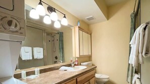 A bathroom with a sink, mirror, and toilet. There are towels hanging on the wall and a shower curtain. - 1BR,1BA for 5 – Close to Outdoor Activities (Brian Head)