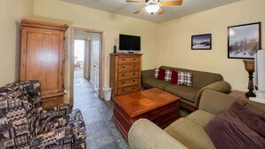 A living room with a sofa, a coffee table, a television, and a ceiling fan. - 1BR,1BA for 5 – Close to Outdoor Activities (Brian Head)