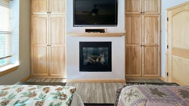 Una habitación con chimenea, televisor montado encima y armarios de madera.