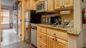 Una cocina con armarios de madera, un refrigerador de acero inoxidable, un microondas y un lavavajillas.