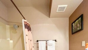 Un baño con ducha envuelta en vidrio, inodoro y tocador con encimera estampada.