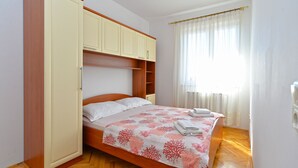 Un dormitorio con cama, armario de madera y ventana con cortinas.