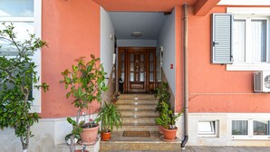 A building entrance with a wooden door, potted plants, and a stone staircase. - Apartment 2224/67734 (Istria - Rovinj), 800m from the beach (Rovinj)