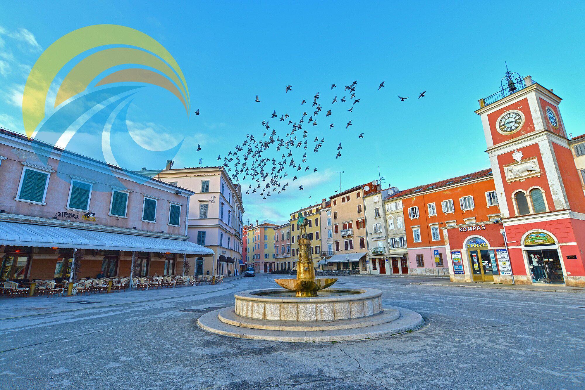 A public square with a fountain, surrounded by historic buildings with shops and a clock tower.