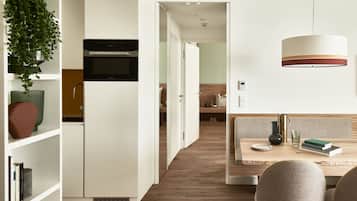 Una cucina moderna con mobili bianchi, forno integrato e zona pranzo con tavolo e sedie in legno.