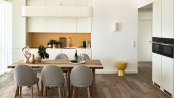 Une cuisine moderne avec des meubles blancs, une table à manger en bois et des chaises grises.