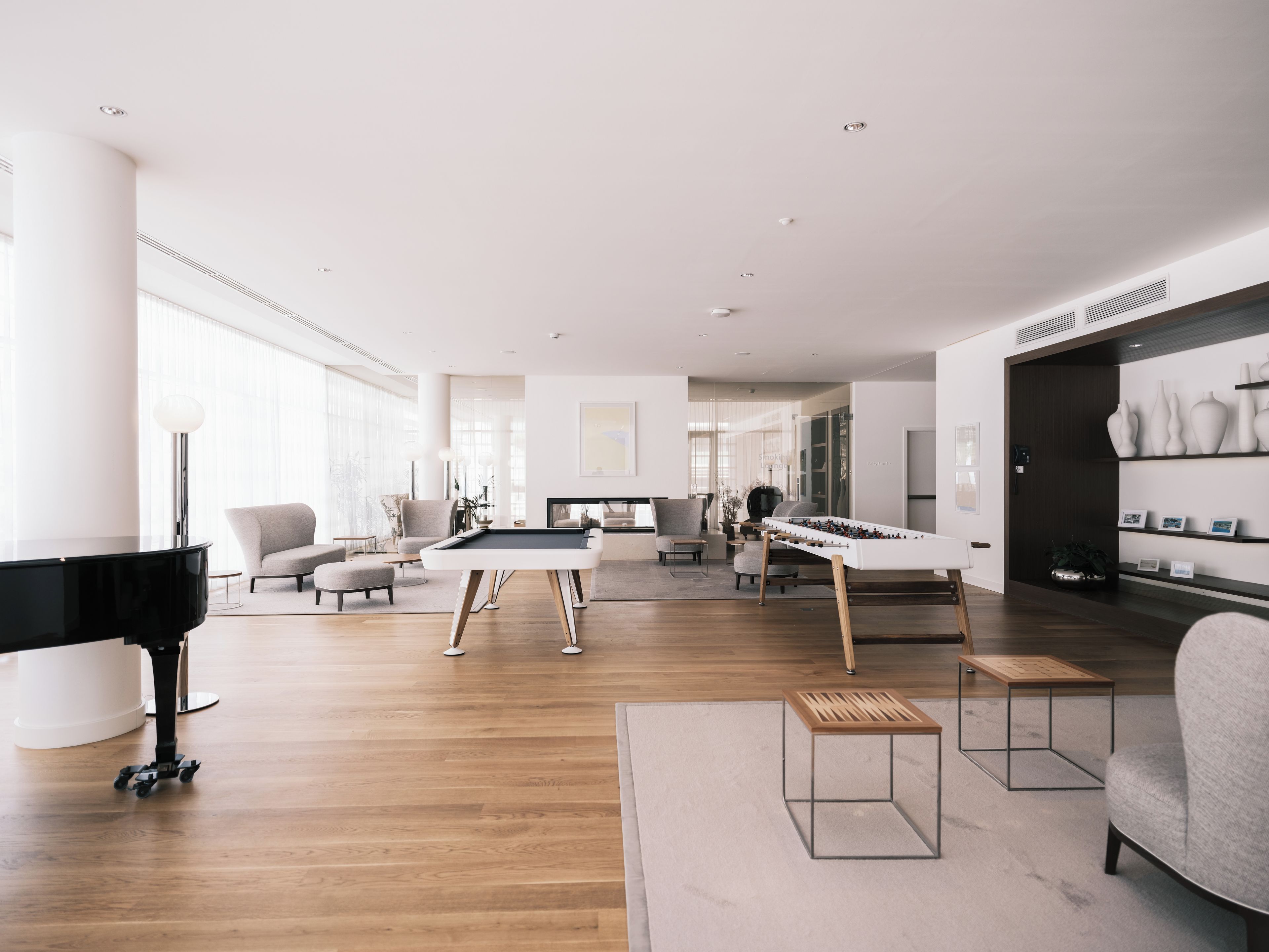 A modern living room with a pool table, a piano, and a sofa.